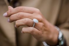 a person wearing a diamond ring on their finger and holding something in his other hand