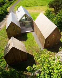 an aerial view of three wooden buildings in the grass