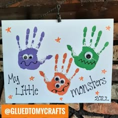 two handprints are hanging from a chain on a sign that says my little monsters