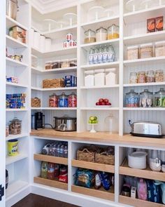 an organized pantry with white shelving and wooden shelves