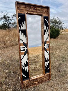 a wooden mirror sitting on top of a dry grass field