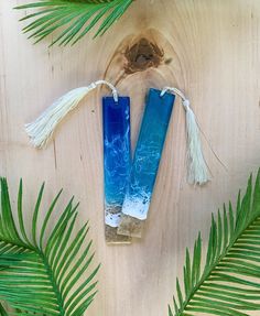 two blue candles sitting on top of a wooden table next to palm leaves and a bird