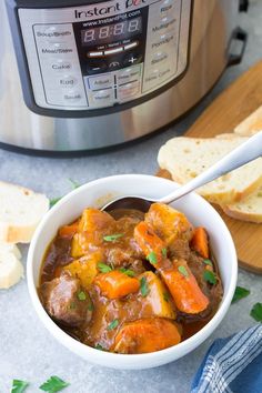 a white bowl filled with stew next to bread and an instant pot pressure cooker