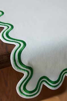 a white table cloth with green lines on it sitting on a wooden chair in front of a window