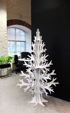 a white tree is in the middle of an office space with black walls and windows