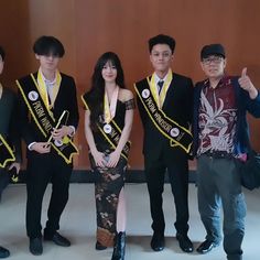 four people standing next to each other in front of a wall with medals around their necks