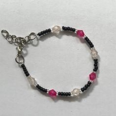 a black and white beaded bracelet with pink glass beads on a silver plated chain