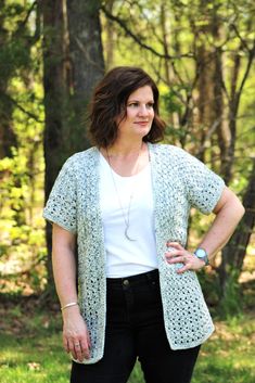 a woman standing in the woods wearing a white top