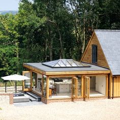 a small wooden house in the middle of a wooded area with an outdoor kitchen and hot tub