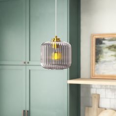 a light hanging from a ceiling in a room with green cupboards and blue walls