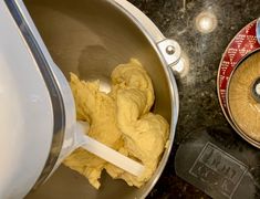 a metal bowl filled with yellow batter next to a measuring cup on top of a counter