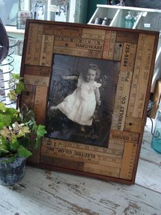 an old photo frame sitting on top of a table next to a potted plant