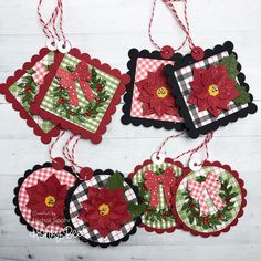 four christmas ornaments hanging from strings on a white wooden surface with red and green decorations