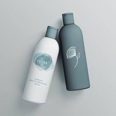 two bottles are sitting next to each other on a gray surface, one is empty and the other has a white flower