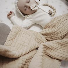 a baby laying on top of a bed with a pacifier in it's mouth