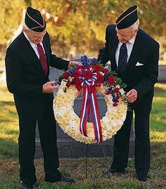 two men standing next to each other in front of a wreath