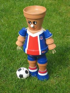 a toy soccer player is standing on the grass with a ball in front of him