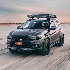 a grey car driving down the road with snow on it's tires and skis mounted to its roof