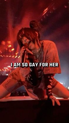 a woman sitting on top of a stage holding a microphone in front of her face