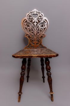 an old wooden chair with ornate carvings on it's back and legs, against a gray background