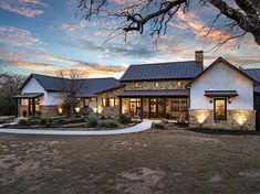 a large white house with lots of windows and lights on it's front porch