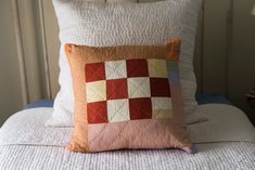 a close up of a pillow on a bed with white linens and a lamp