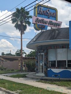 the front of a coffee shop with palm trees in the foreground and blue sky