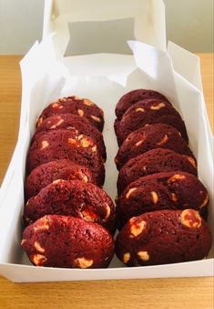 a box filled with red velvet cookies on top of a wooden table