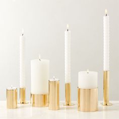 candles are lined up in gold and white holders