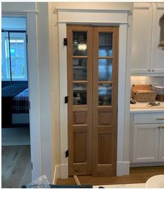 a kitchen with white cabinets and wooden doors in the center, along with an open pantry