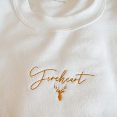 "Welcome to The Shop Between Worlds!! This design is inspired by Aelin \"Fireheart\" Ashryver Whitethorn Galathynius; the main character of the series Throne of Glass. Embroidered in gold thread, this shirt features the word \"Fireheart\" written in a beautiful script font, as well as a stag, inspired by the symbol of the kingdom of Terrasen. A must have for any member of the Court of Terrasen! A sturdy and warm sweatshirt bound to keep you warm in the colder months. A pre-shrunk, classic fit sw Throne Of Glass Sweatshirt, Throne Of Glass Tattoo Fireheart, Throne Of Glass Jewelry, Throne Of Glass Embroidery, Fireheart Tog Tattoo, Throne Of Glass Merch, Aelin Galathynius Tattoo, Throne Of Glass Tattoo, Aelin Fireheart