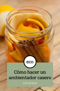 a jar filled with oranges and cinnamon sticks on top of a wooden table next to an apple