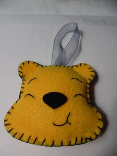 a yellow bear ornament hanging from a white ribbon