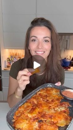 a woman holding up a pan with food on top of it in front of her