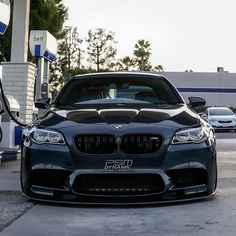 a black bmw parked at a gas station