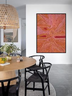 a dining room table with chairs and artwork on the wall