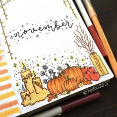 an open notebook with pumpkins and candles on it, next to two pencils