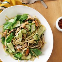 a white bowl filled with pasta and veggies on top of a wooden table