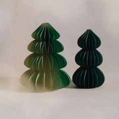 two green paper christmas trees sitting next to each other