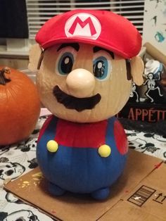 a close up of a statue of mario on a table with pumpkins in the background