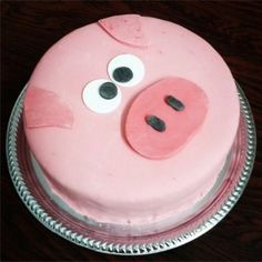 a pink cake with googly eyes and nose is on a plate, ready to be eaten