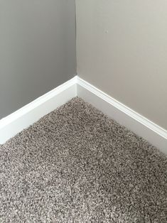 the corner of a room with carpet on the floor and walls painted gray, white and black