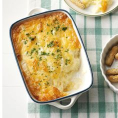 a casserole dish with cheese on top and other dishes next to the casserole