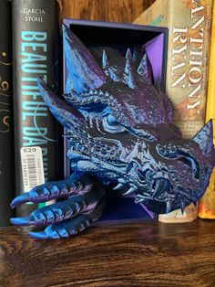 a blue dragon head sitting on top of a wooden table next to books and a computer mouse