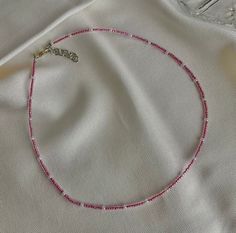 a pink beaded necklace laying on top of a white cloth