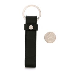 a black leather keychain with a coin on the side and a white background