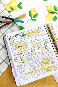 a recipe book with lemons on it next to markers and pens, along with other kitchen utensils