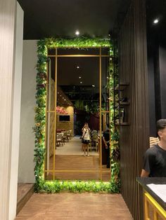 a man sitting at a table in front of an open door with greenery on it