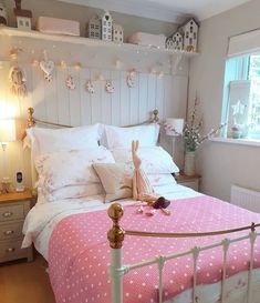 a bed with pink and white bedspread in a bedroom next to a window