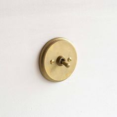 a white wall with a gold colored knob on it's left side and a black button on the right side